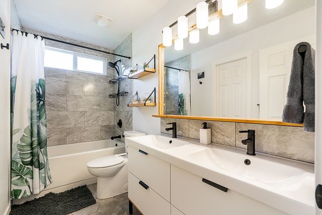 Full bath featuring shower / tub combo, double vanity, toilet, and decorative backsplash | Image 24