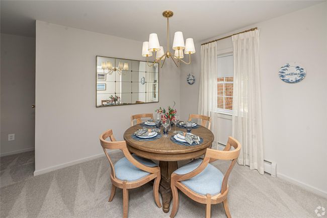Dining room with a chandelier, a baseboard heating unit, carpet flooring, and baseboards | Image 4
