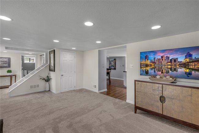 Recessed lighting, plush carpet, & neutral paint in the living room. | Image 9