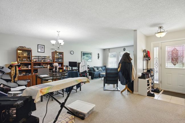 Carpeted entrance foyer featuring a chandelier and a textured ceiling | Image 11