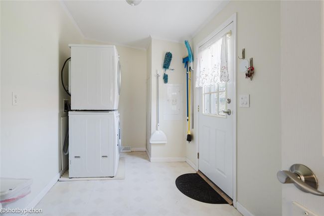 Entryway with light flooring, stacked washer and clothes dryer, and crown molding | Image 16