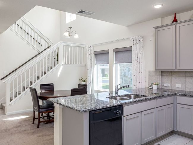 Kitchen with black dishwasher, a sink, gray cabinetry, light stone countertops, and tasteful backsplash | Image 10