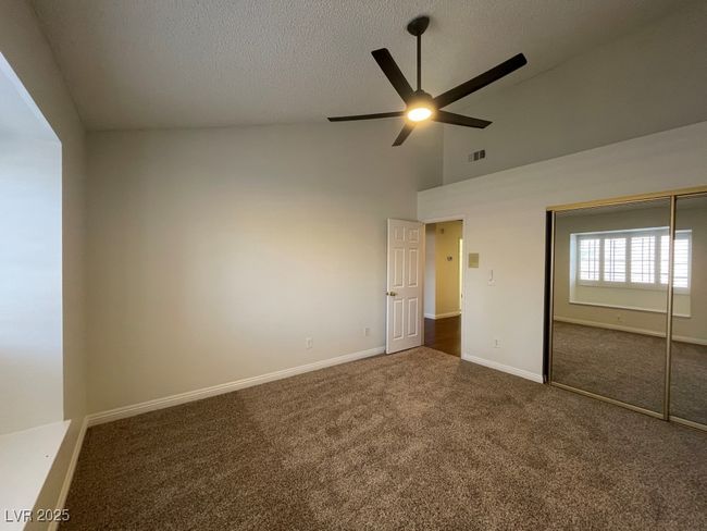 Unfurnished bedroom featuring carpet, high vaulted ceiling, a closet, a textured ceiling, and a ceiling fan | Image 22