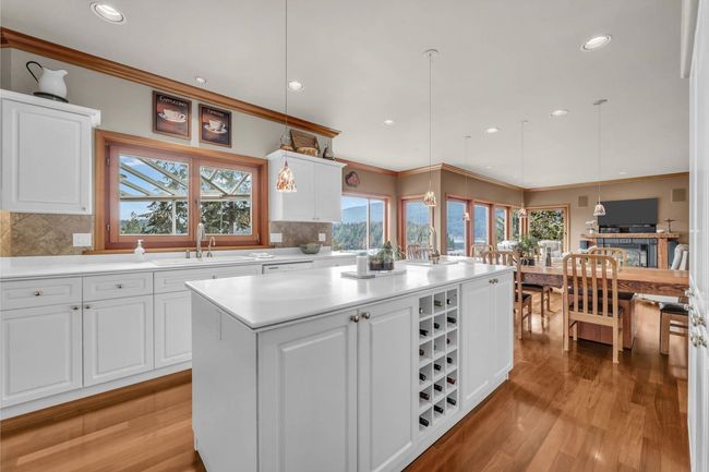 Kitchen with white cabinetry, light wood-style floors, a center island, and a sink | Image 19