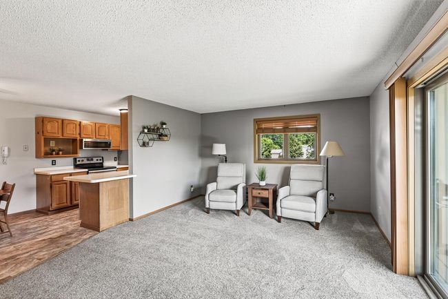The generously sized living room offers newer carpet that includes an extra thick pad to provide comfort underfoot. To the right you will see the sliding glass door which fills the space with natural light. | Image 5