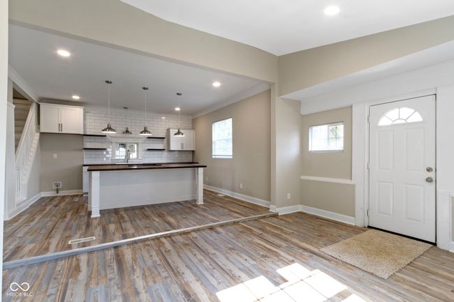 kitchen with dark countertops, decorative backsplash, white cabinets, light wood-style flooring, and baseboards | Image 8