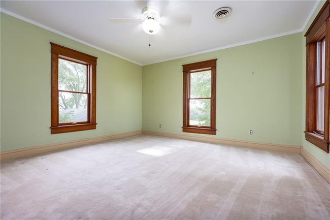 Carpeted spare room featuring ornamental molding, ceiling fan, and plenty of natural light | Image 25