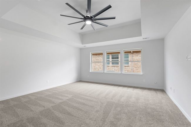 Carpeted spare room with baseboards, visible vents, a raised ceiling, and ceiling fan | Image 23