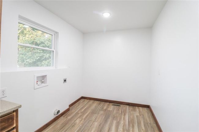 Laundry area with light wood-type flooring, hookup for a washing machine, cabinets, and electric dryer hookup | Image 21