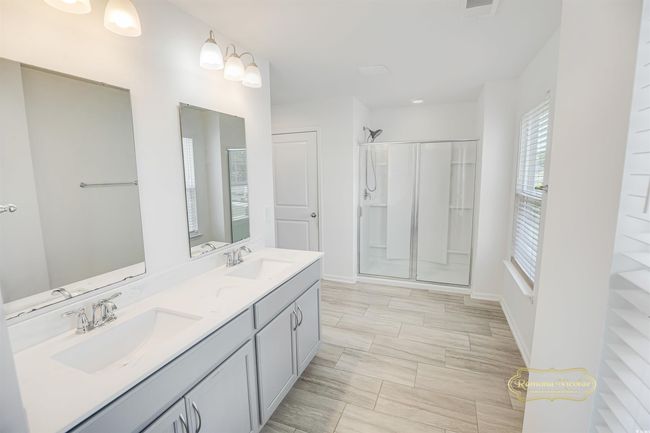 Full bathroom featuring double vanity, a shower, and baseboards | Image 22