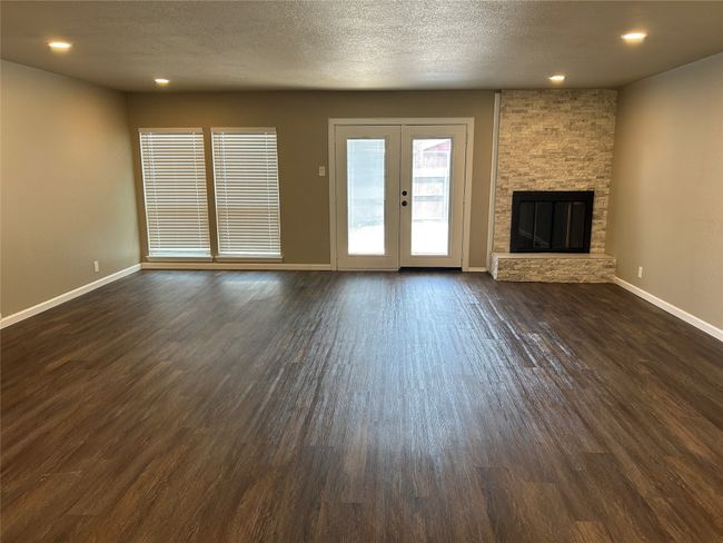 Unfurnished living room featuring dark wood-style flooring, baseboards, a fireplace, recessed lighting, and french doors | Image 14