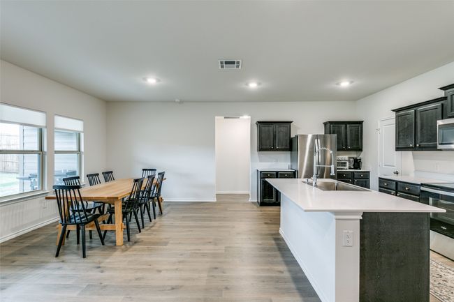Kitchen with light hardwood / wood-style floors, stainless steel appliances, sink, and a kitchen island with sink | Image 10