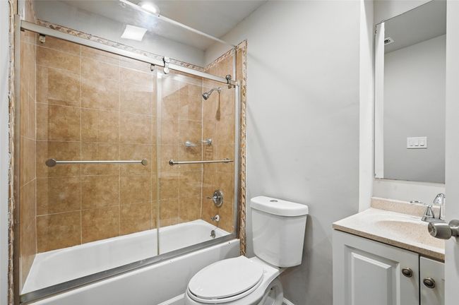 Full bathroom with toilet, bath / shower combo with glass door, and vanity | Image 11