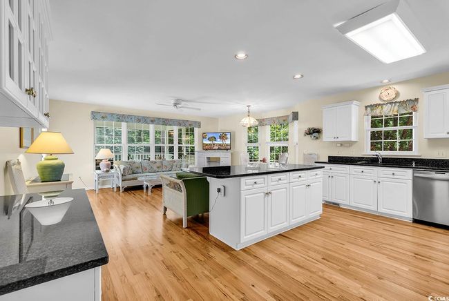Kitchen with stainless steel dishwasher, light wood-style floors, white cabinetry, open floor plan, and a center island | Image 19