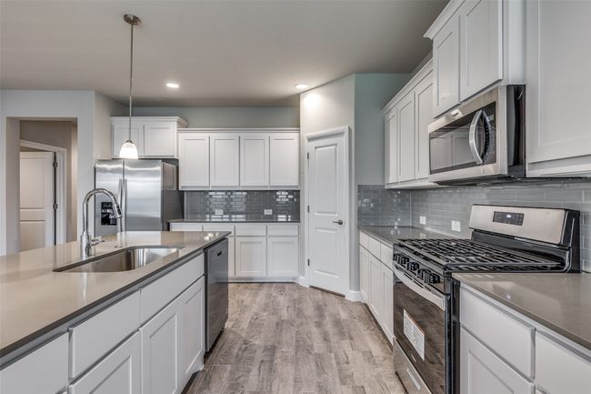 Kitchen with stainless steel appliances, sink, white cabinetry, and light wood-type flooring | Image 7