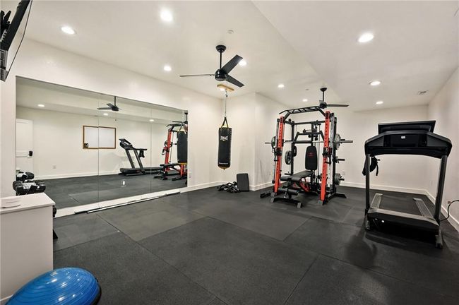 Workout room featuring ceiling fan, mirrored wall and exercise mat flooring. | Image 46