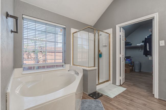 Bathroom featuring a garden tub, a stall shower, vaulted ceiling, a spacious closet, and healthy amount of natural light | Image 30