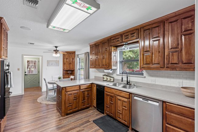 Kitchen with stainless steel dishwasher, decorative backsplash, a peninsula, and dark wood-type flooring | Image 11