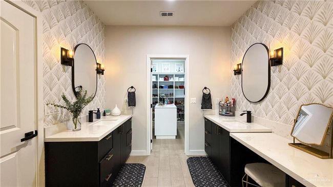 Full bathroom with wallpapered walls, two vanities, an accent wall, and wood finished floors | Image 12