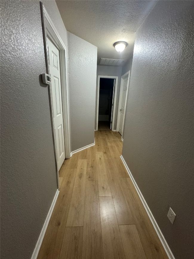 Corridor featuring light wood-style floors, baseboards, and a textured wall | Image 19