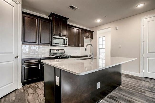 Kitchen with visible vents, a sink, wood finished floors, stainless steel appliances, and decorative backsplash | Image 9