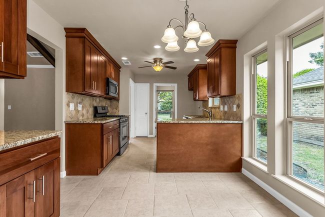 Kitchen with appliances with stainless steel finishes, tasteful backsplash, a ceiling fan, light stone counters, and recessed lighting | Image 12