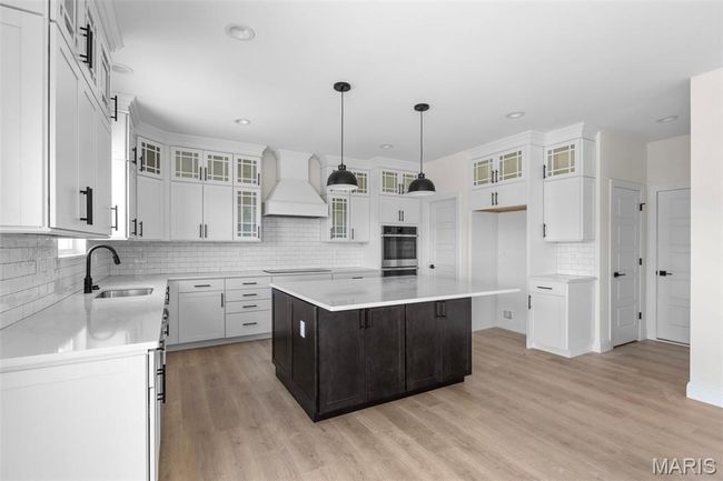 Kitchen featuring premium range hood, stainless steel oven, backsplash, a center island, and light wood-style flooring | Image 19
