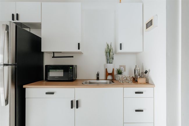 Wet bar with white cabinetry, sink, and stainless steel refrigerator | Image 25