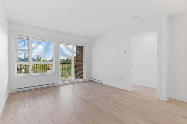 Empty room with a baseboard heating unit, healthy amount of natural light, and light wood finished floors | Image 10