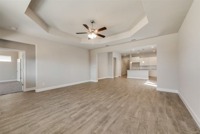 Unfurnished living room with ceiling fan, a tray ceiling, and light wood-type flooring | Image 9