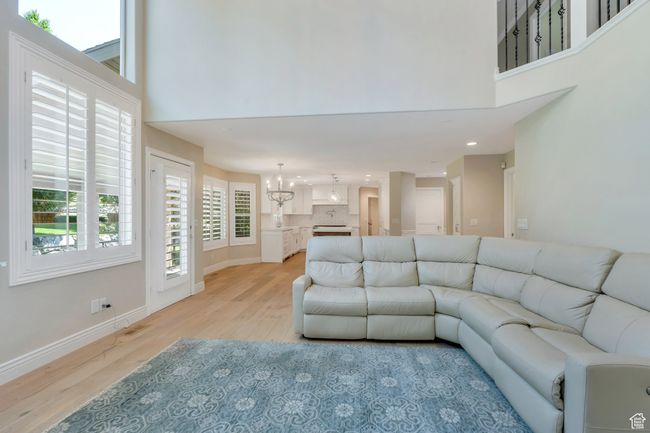 Living area featuring light wood finished floors, a high ceiling, a chandelier, healthy amount of natural light, and recessed lighting | Image 10