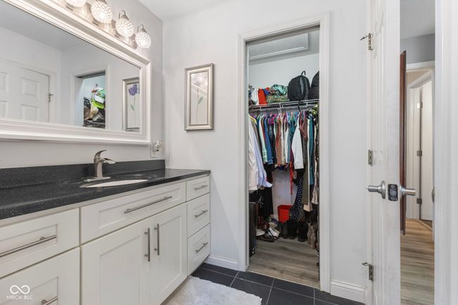 bathroom with tile patterned flooring, vanity, and a walk in closet | Image 24