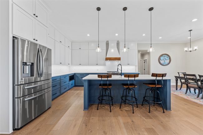 Kitchen with crown molding, custom range hood, decorative backsplash, and stainless steel fridge | Image 6