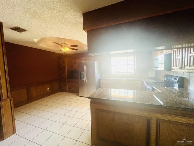 Kitchen with a textured ceiling, appliances with stainless steel finishes, ceiling fan, decorative backsplash, and kitchen peninsula | Image 7