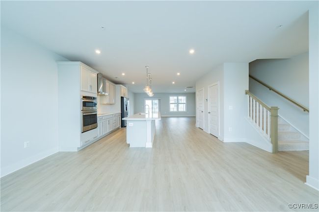Kitchen with open floor plan, a sink, light countertops, recessed lighting, and an island with sink | Image 23