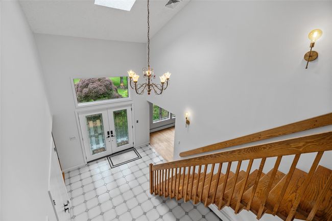 Stairs with high vaulted ceiling, french doors, a chandelier, baseboard heating, and a skylight | Image 21