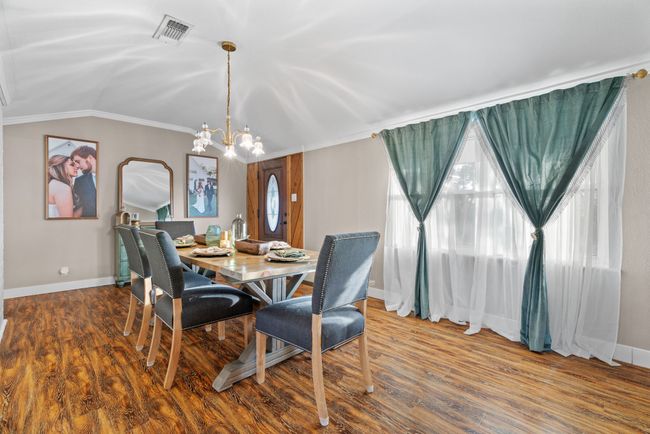 Dining room with crown molding, vaulted ceiling, a chandelier, and wood finished floors | Image 7