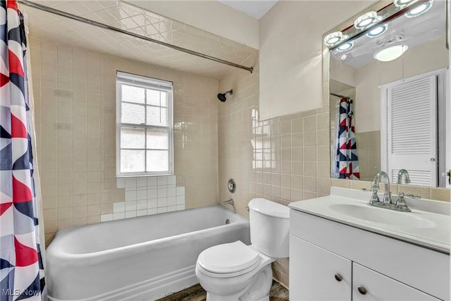 Bathroom featuring shower / bath combo, toilet, vanity, and tile walls | Image 33