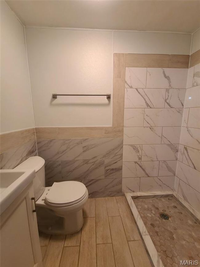Bathroom with a shower stall, vanity, tile walls, and a wainscoted wall | Image 22