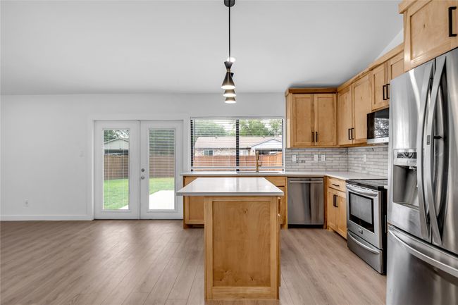 Kitchen with appliances with stainless steel finishes, a sink, light countertops, a kitchen island, and light wood finished floors | Image 17