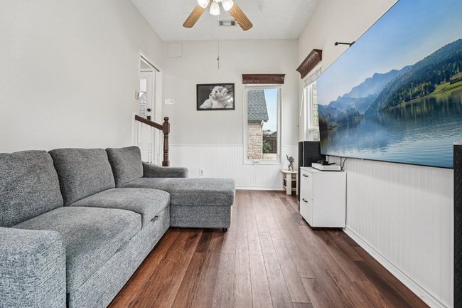 Living area with dark wood-style floors, ceiling fan, and a wainscoted wall | Image 7