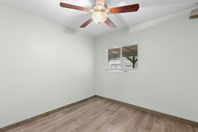 Empty room with light wood-style flooring, a textured ceiling, and ceiling fan | Image 21