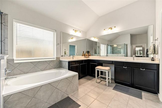 This additional view of the primary bath showcases the vanity with a large mirror and a separate garden tub perfect for soaking after a long day. | Image 14