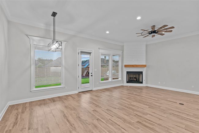 Unfurnished living room with crown molding, a large fireplace, light wood-type flooring, recessed lighting, and ceiling fan | Image 5