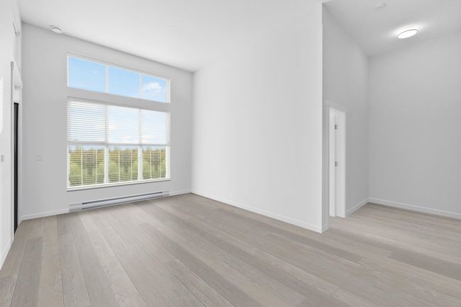 Empty room with baseboard heating, baseboards, and light wood-style floors | Image 4