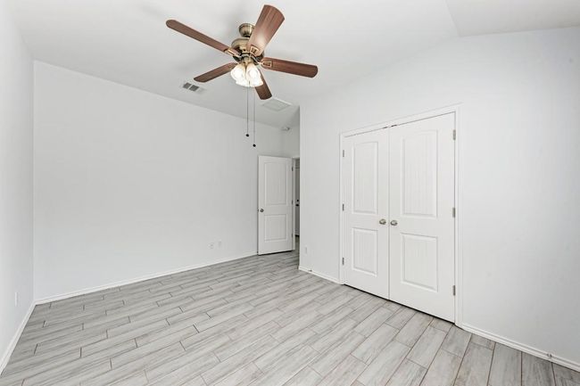 Second and third bedroom featuring light wood finished floors, a closet, baseboards, ceiling fan, and vaulted ceiling | Image 30