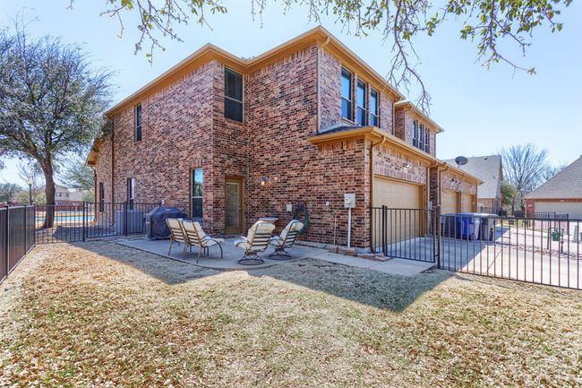 Rear view of house with a patio, fence, driveway, a garage, and brick siding | Image 32