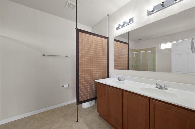 Spacious walk-in closet with ample hanging space and built-in shelving, perfect for organized storage. The room features neutral walls and dark wood flooring. | Image 19