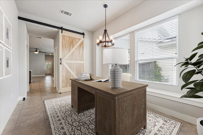 Home office with a barn door, baseboards, light tile patterned floors, a ceiling fan, and a chandelier | Image 4