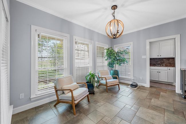 Living area featuring a chandelier, baseboards, ornamental molding, and stone tile flooring | Image 13